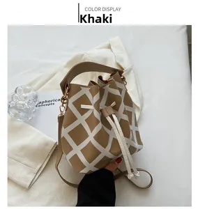 Detail of khaki bucket bag with large white quilted pattern on a white blazer