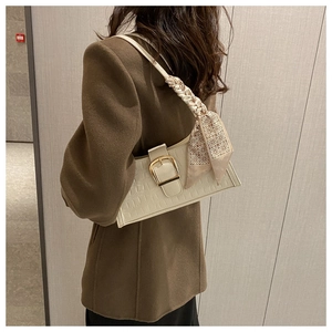 Close-up of white crocodile pattern underarm bag with silk scarf handle and gold buckle