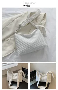 Detailed close-up of white quilted tote bag with silver chain strap and knot detail