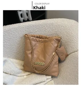 Detail of khaki quilted chain tote bag with mini coin purse on a soft fabric sofa