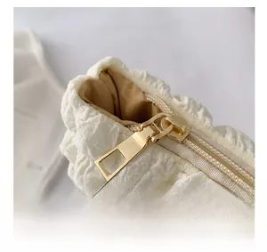 Dettaglio della cerniera scorrevole sulla borsa tote crema con trama in tessuto a bolle