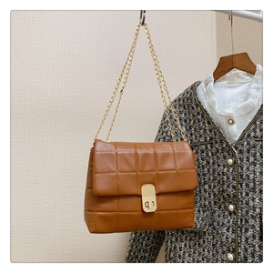 Close-up of brown quilted leather bag with square texture and golden chain strap