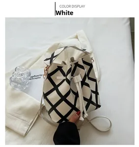 Detail of a minimalist cream bucket bag with black grid pattern and drawstring closure