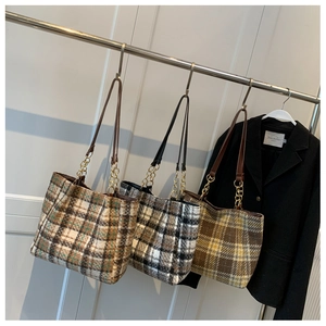 Détail de sacs cabas à carreaux avec bandoulières en cuir et accents de chaîne dorée