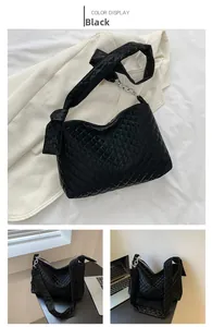 Detail view of the black quilted shoulder bag featuring a wide strap and metal chain