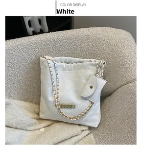 Close-up of white quilted tote bag with gold chain strap and matching mini coin purse