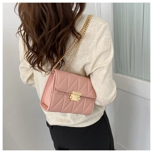 Detail of pink quilted leather bag with gold chain strap worn by a model