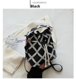 Detail view of black and white checkered drawstring bucket bag with leather strap