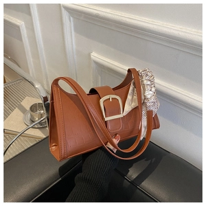 Close-up of caramel brown crocodile embossed handbag with gold buckle and silk scarf