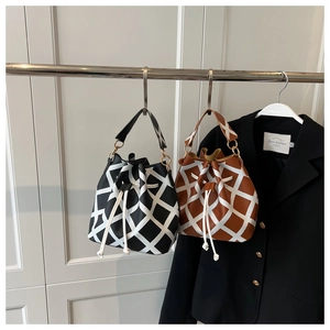 Detail of minimalist bucket bags in black and brown with bold white checkered patterns