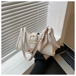Close-up of white crocodile pattern shoulder bag with gold buckle and decorative silk scarf