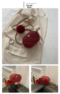 Detail of red quilted crossbody bag with gold floral clasp and plush pom-pom charm