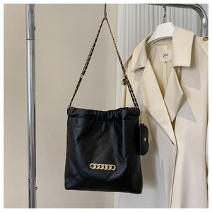 Detail of black quilted leather tote with gold chain and small side pouch hanging