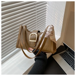 Detail of caramel crocodile pattern underarm bag with gold buckle and silk scarf