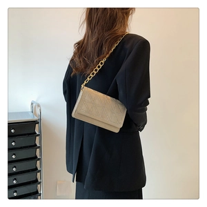 Detail of beige quilted velvet shoulder bag with silver studs and gold chain strap