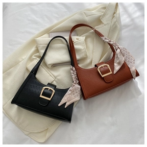 Detail of crocodile embossed shoulder bags with metal buckles and decorative silk scarves