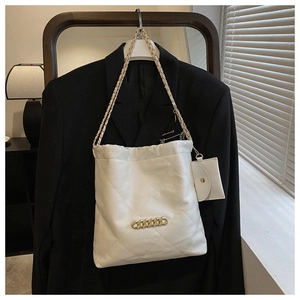 Close-up of white quilted shoulder bag with gold chain and matching mini pouch