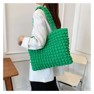 Dettaglio della borsa tote verde brillante con trama a bolle e ampia tracolla a pieghe