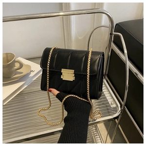 Close-up of black quilted leather bag featuring a gold rectangular metal clasp and chain