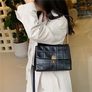 Classic black quilted chain bag with gold twist lock worn as a stylish crossbody