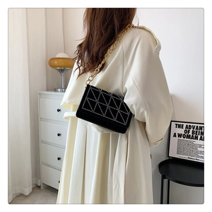 Detailed view of a black velvet chain bag with silver studs and gold metal strap