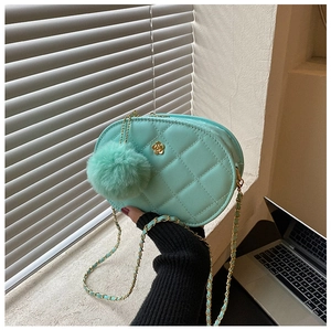 Detail of mint green quilted oval bag with golden camellia buckle and plush charm pendant