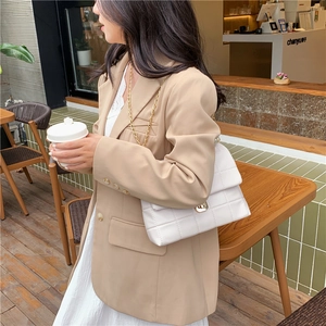 Minimalist white quilted chain bag worn with a light camel blazer in a cafe setting