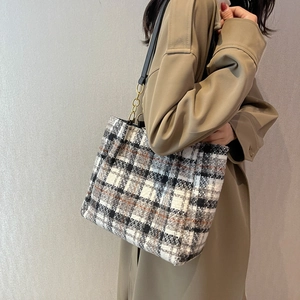 Sac cabas à carreaux en tweed avec chaîne dorée porté sur un trench-coat beige élégant