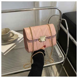 Close-up of light pink quilted leather handbag with gold metal clasp and chain strap