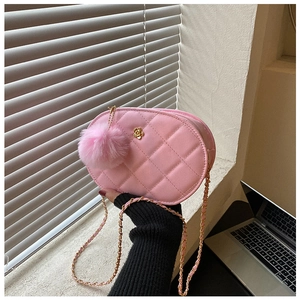 Detailed macro of pink quilted oval bag featuring a gold camellia clasp and chain strap