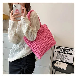 Dettaglio della borsa tote rosa con trama popcorn e tessuto a bolle 3D sulla tracolla