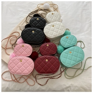 Close-up of quilted oval crossbody bags with camellia gold hardware and plush charm
