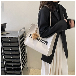 Close-up of stylish white tote bag with FASHION print and brown faux fur charm