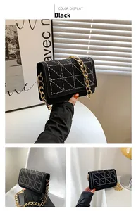 Detail of black velvet shoulder bag featuring triangle stud patterns and gold chain