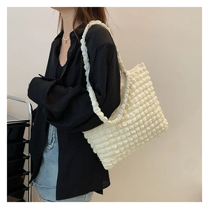 Dettaglio del tessuto bianco a trama popcorn su una grande borsa a tracolla tote da donna