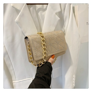 Detail of beige velvet shoulder bag with silver rivet triangles and golden chain strap