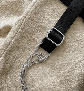 Detail of silver chain strap and black nylon webbing on off-white teddy fleece waist bag