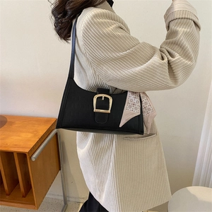 Minimalist black faux leather underarm bag with gold buckle and silk scarf detail