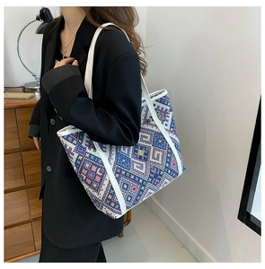 Detailed macro of a woven tote bag with colorful ethnic geometric patterns and white leather straps