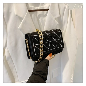 Detail of black velvet shoulder bag with silver rivet triangles and golden chain strap