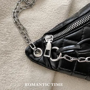 Detail of black quilted leather waist bag with smooth silver metal zipper and chain