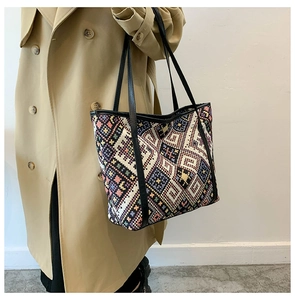 Close-up of ethnic woven tote bag with colorful geometric patterns and black leather straps