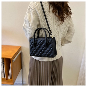 Detail of vintage black heart-quilted crossbody bag with dual handles and gold hardware