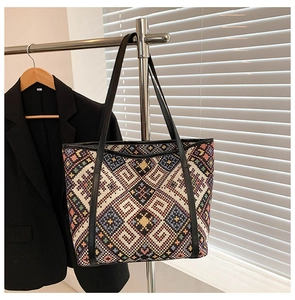 Close-up of bohemian woven tote bag featuring colorful geometric patterns and slim black straps