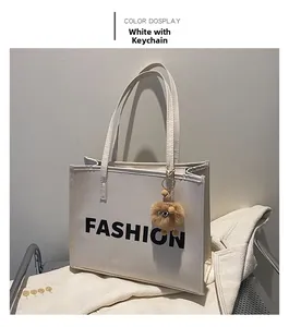 Detail of white leather tote bag with FASHION lettering and brown faux fur pompom charm