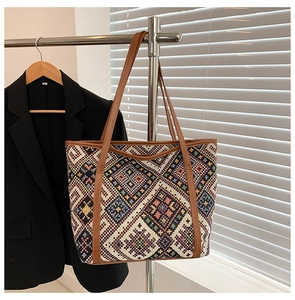 Detailed close-up of a large ethnic woven tote bag hanging on a minimalist metal rack