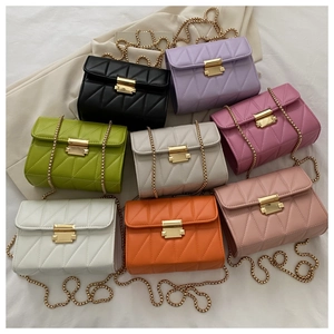 Flat lay of colorful quilted crossbody bags with gold chains on white fabric background