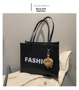 Detailed view of a black tote bag with white FASHIO text and a brown fur charm