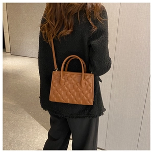 Close-up of brown PU leather bag with heart-quilted pattern worn by model