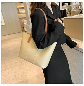 Detail of minimalist cream tote bag showing contrast stitching and brown leather shoulder strap